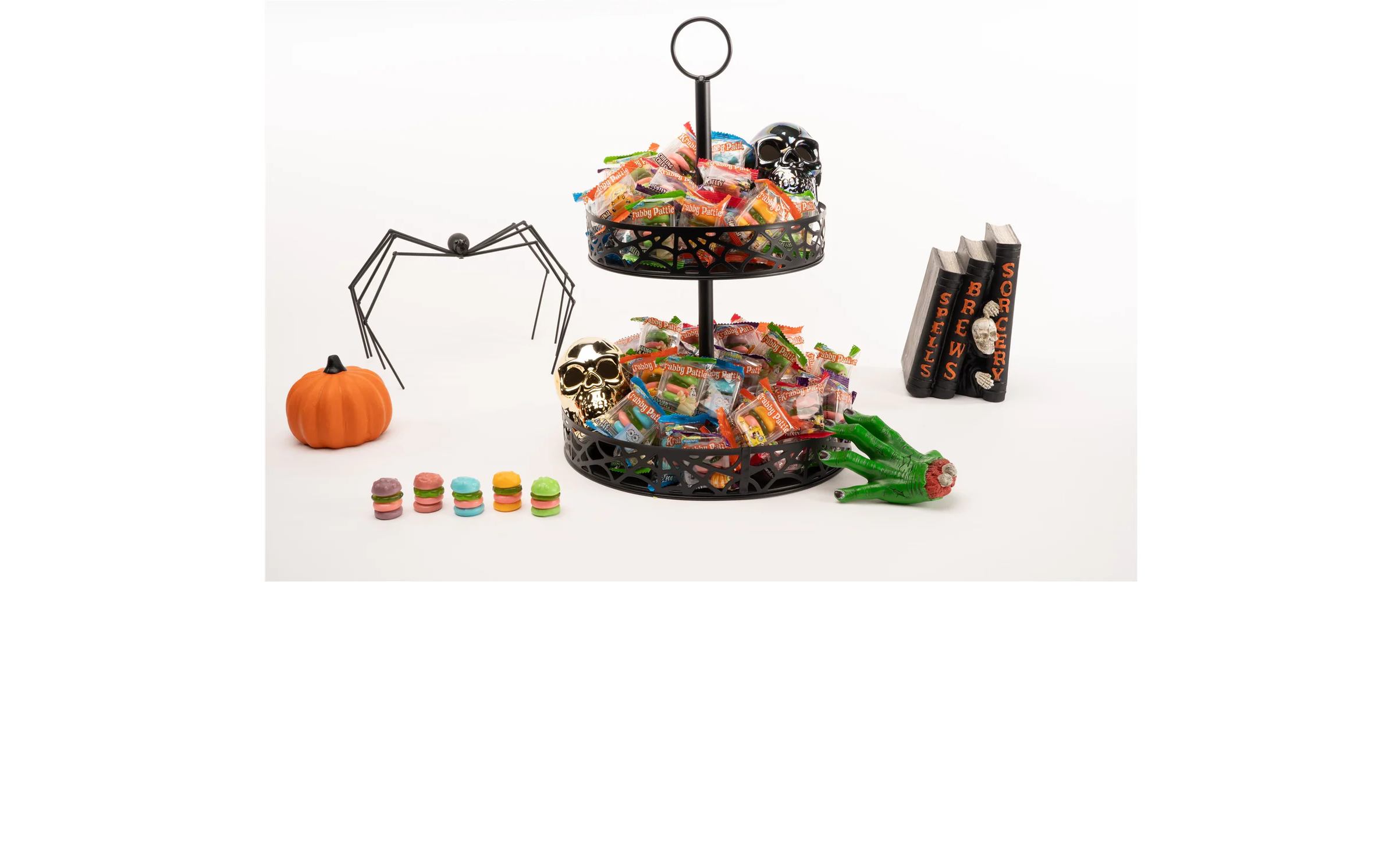 Unwrapped body parts gummies displayed on a platter with fake blood around it and a severed green hand, skulls, and a rat on the floor below
