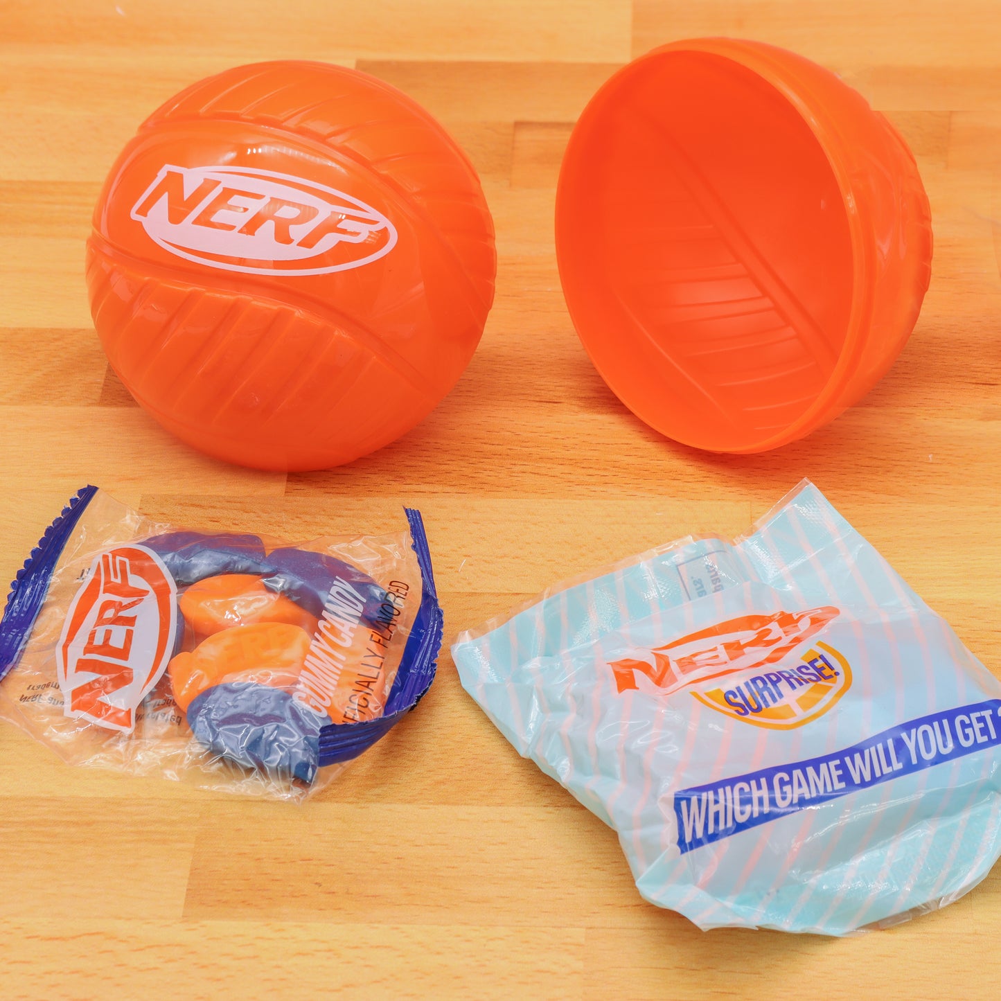 Opened orange nerf ball with bag of nerf hard candy and a blue nerf packet