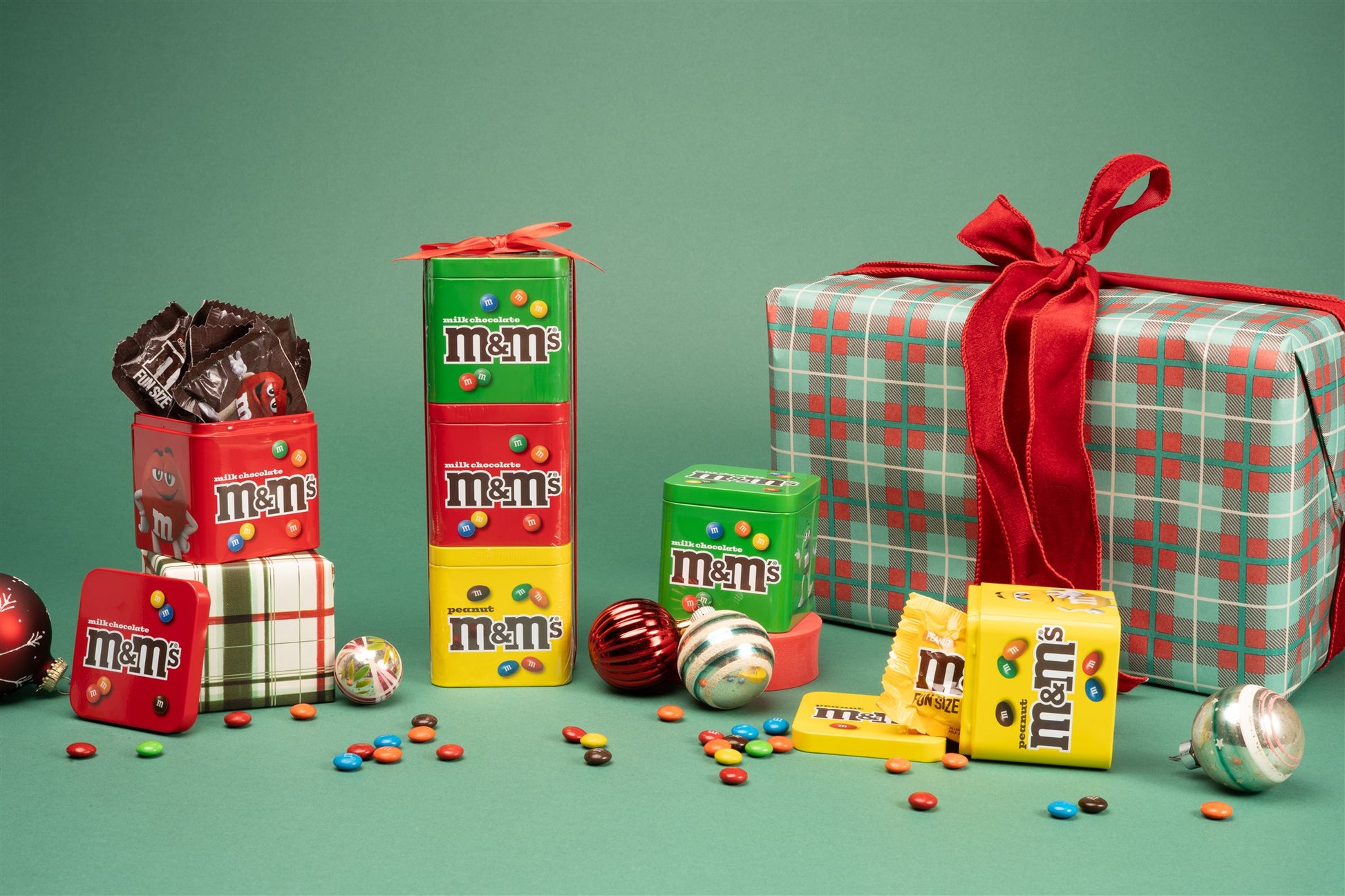 Gift set and tins staged in a holiday background with ornaments and a present 