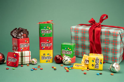Gift set and tins staged in a holiday background with ornaments and a present 