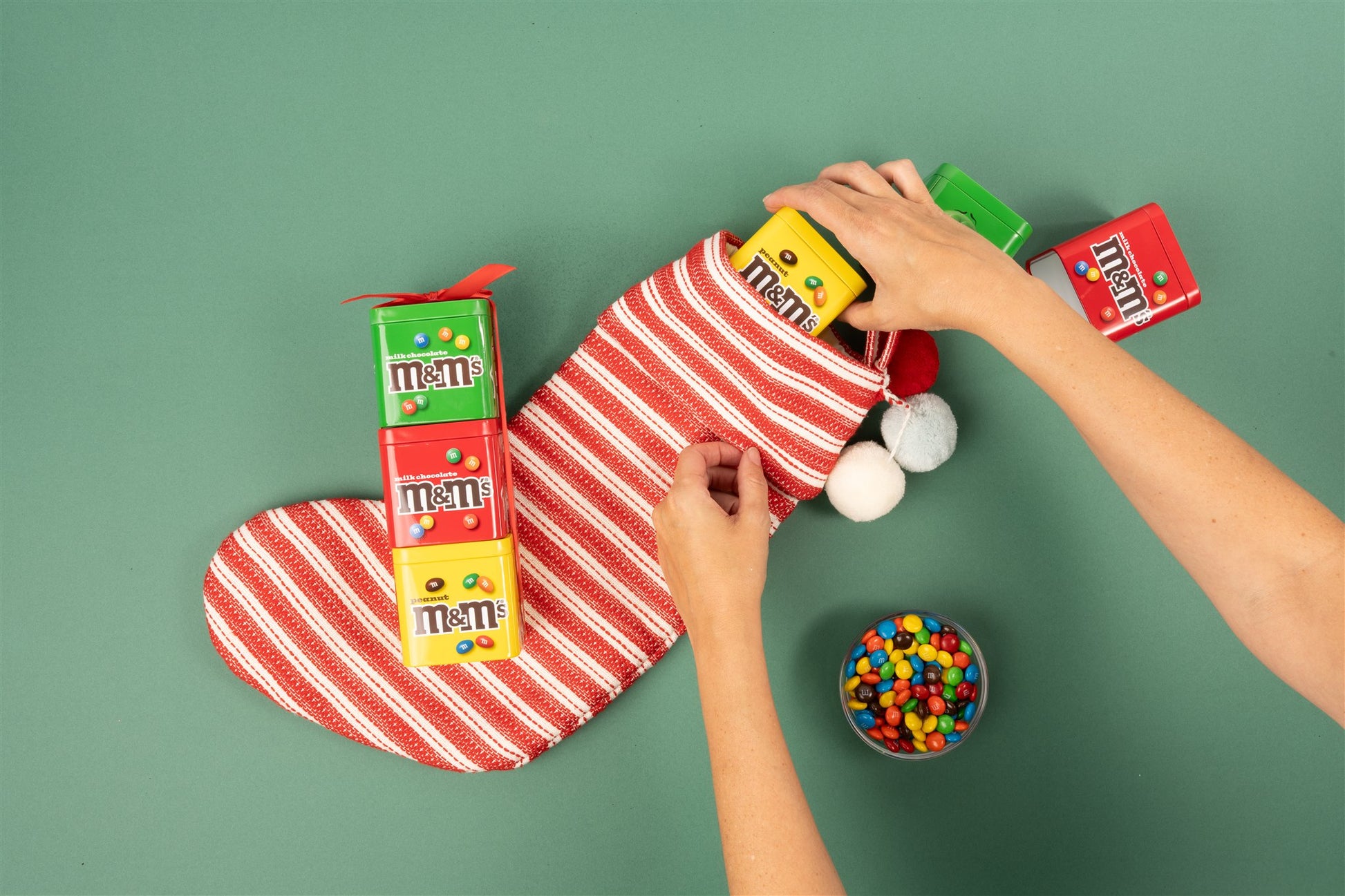 Individual tins getting put into a christmas stocking with a gift set laid down on top 