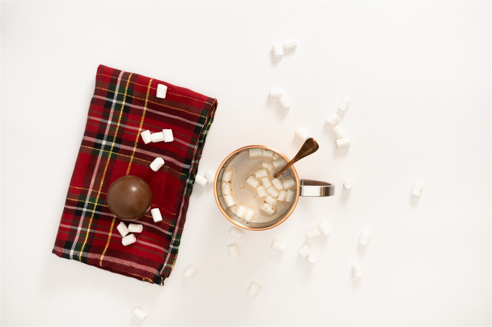 Hot chocolate bomb with marshmallows around it and a cupe of hot chocolate with marshmallows in it 