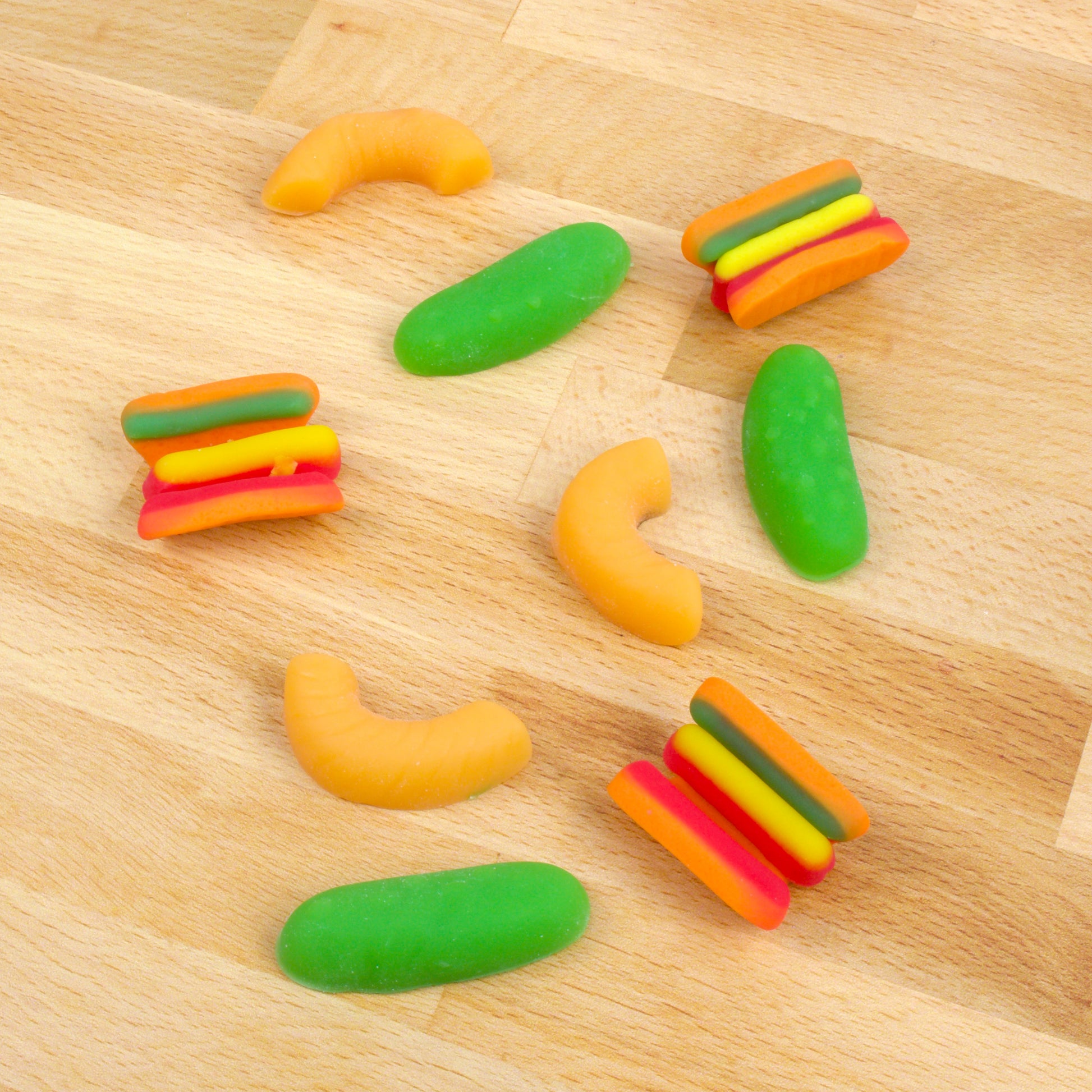 pickle, hot dog, and mac and cheese shaped gummies on hardwood