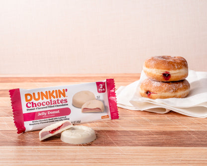 white and pink package with Dunkin Jelly Donut 2 Pack Chocolates and 2 actual jelly donuts in background  on top of folded white napkin