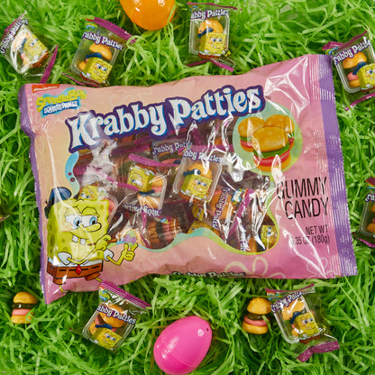 purple and pink krabby patties bag in grass surrounded by plastic eggs and individually wrapped krabby patties gummies