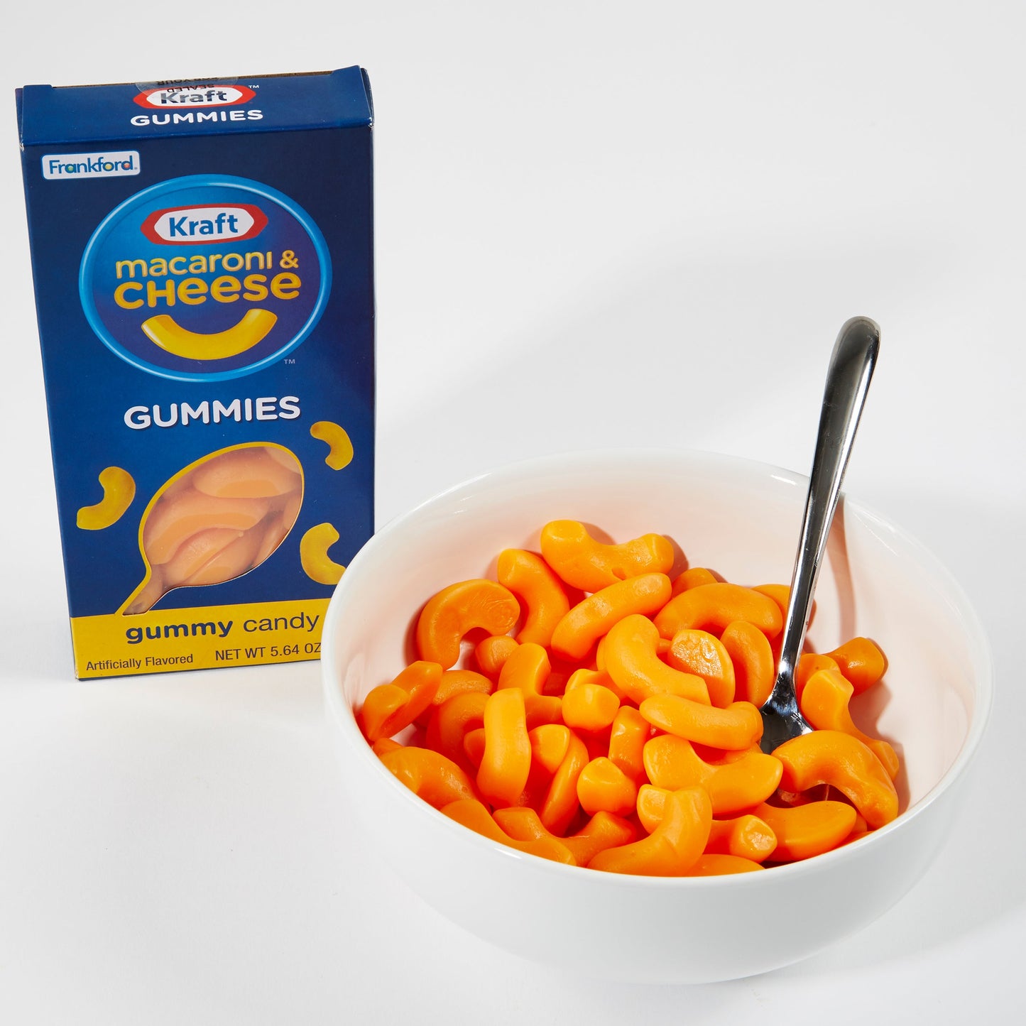white bowl of mac and cheese gummies with blue gummies box
